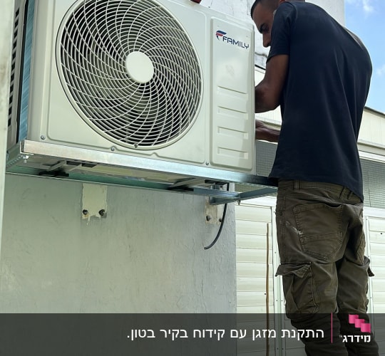 טכנאי מתקין מזגן על קיר חיצוני